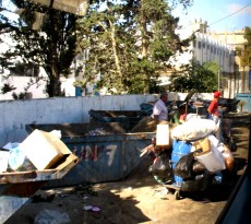 overflowing garbage dumpster labeled "UN"